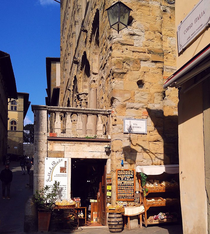 A shop doorway with products outside, built into the basement of Arezzo's church