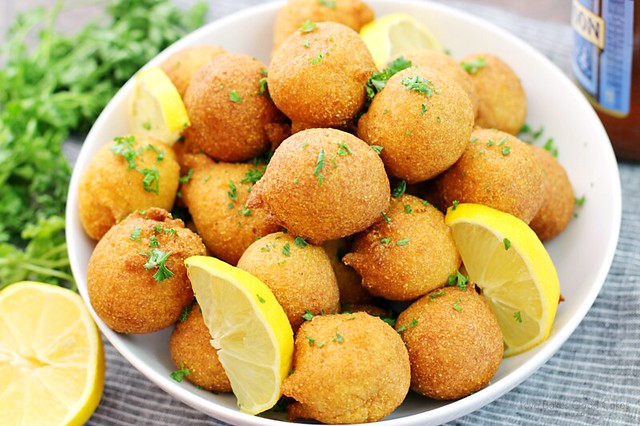 Classic Hush-puppies in a white bowl with slices of lemon.