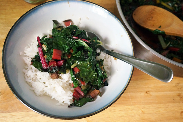 A bowl of simple Swiss chard with garlic and crystallized ginger, the saucepan of greens partially visible at the edge of the frame